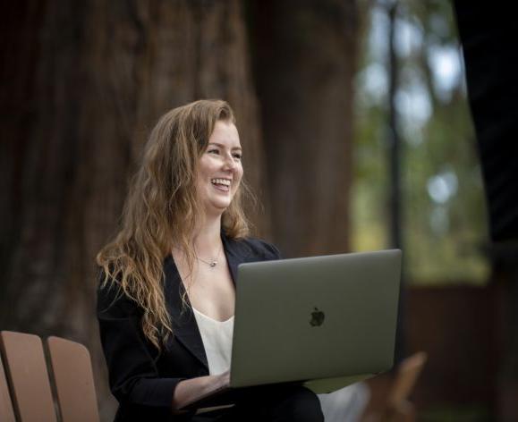 student with laptop sitting on chair outside